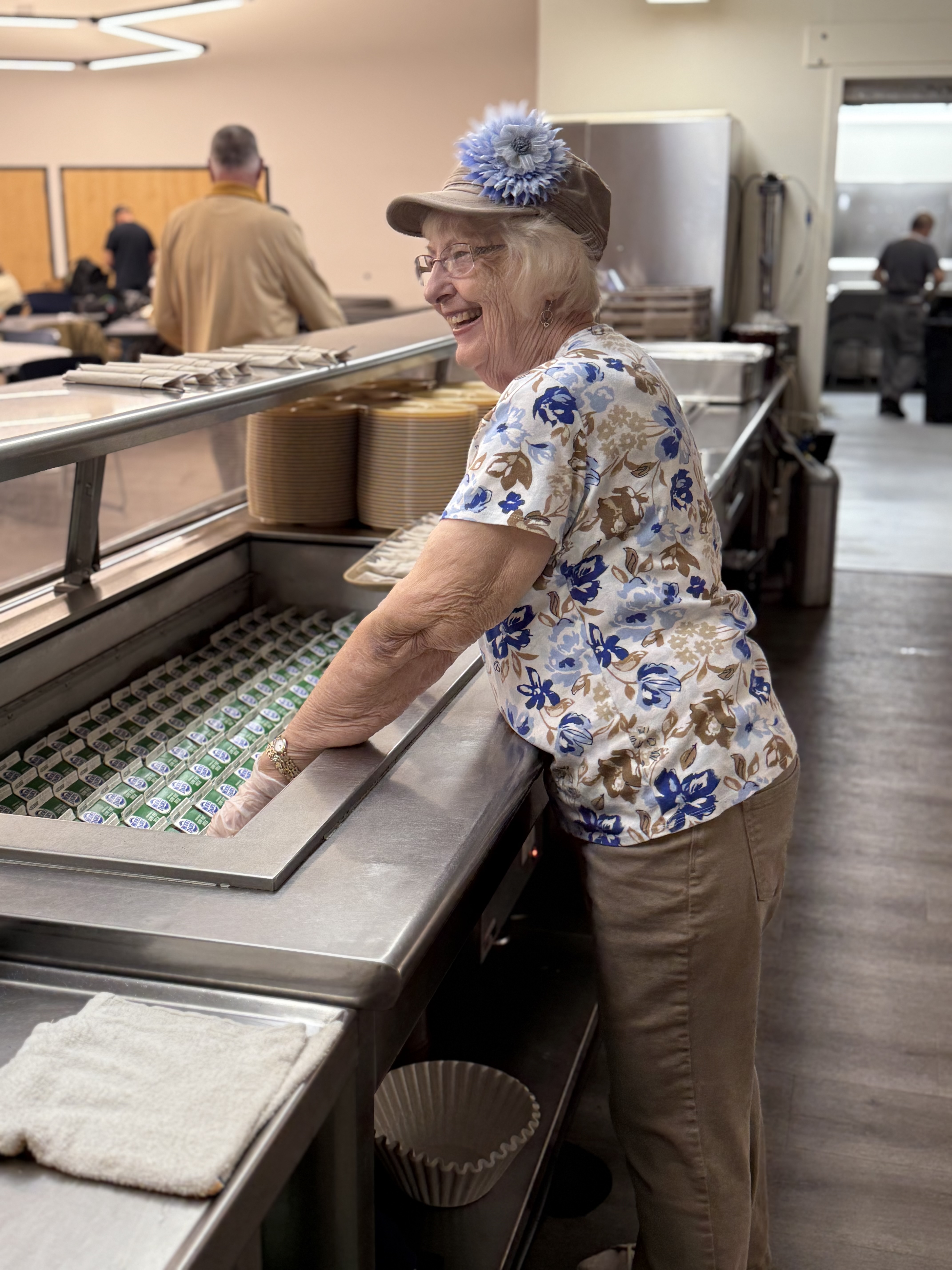 Image of a worker behind the lunch service counter, serving milk
